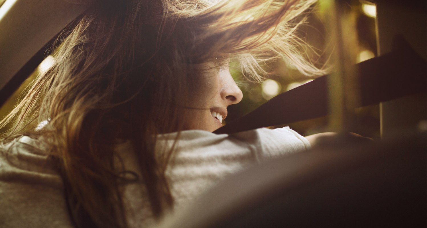 SEAT new car services – Wide shot of woman stepping out of a car hair blowing