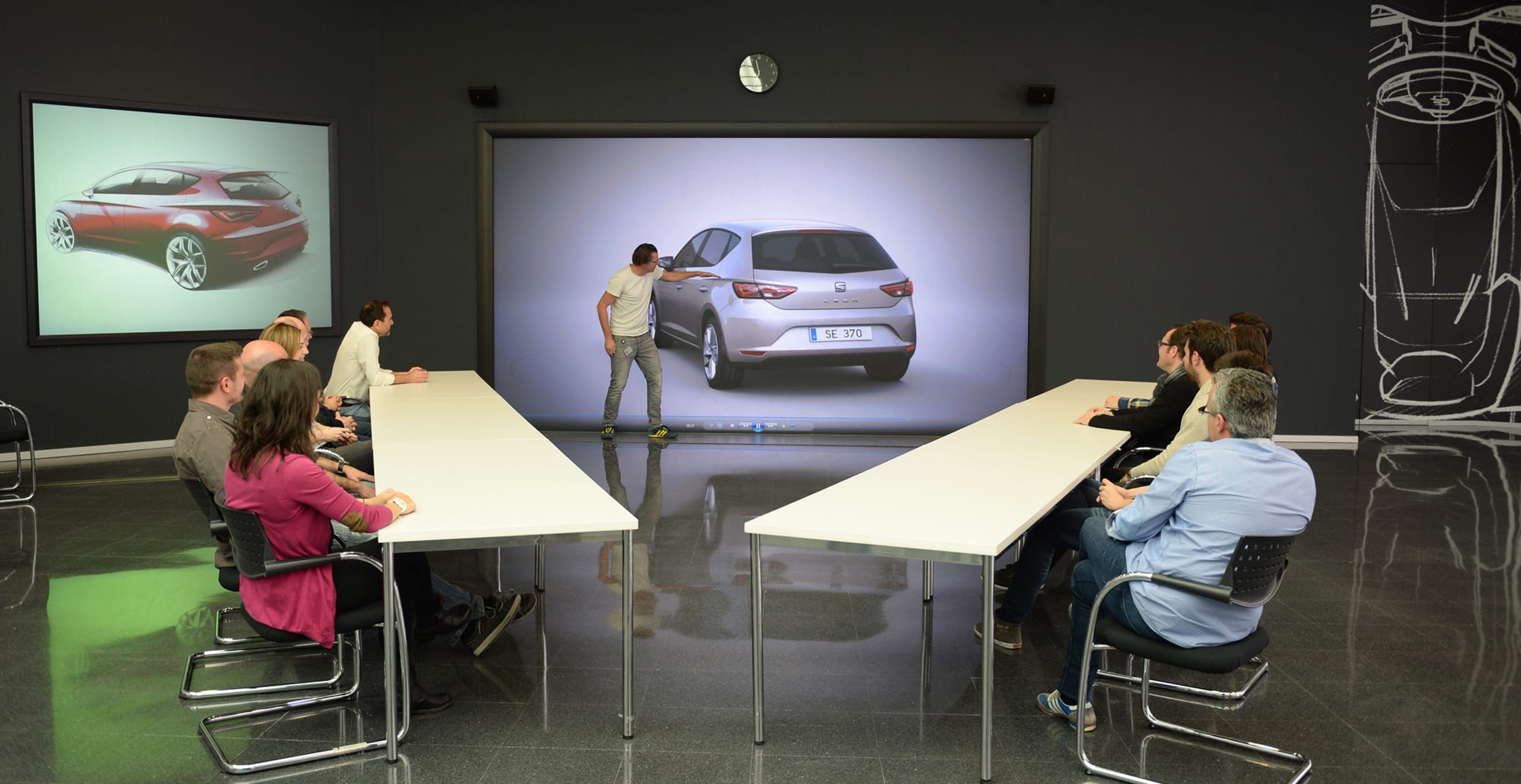 Mesa redonda discusión de un hombre que apunta al diseño del auto SEAT Leon con un grupo de personas mirando sentado en una mesa - SEAT Human Resources
