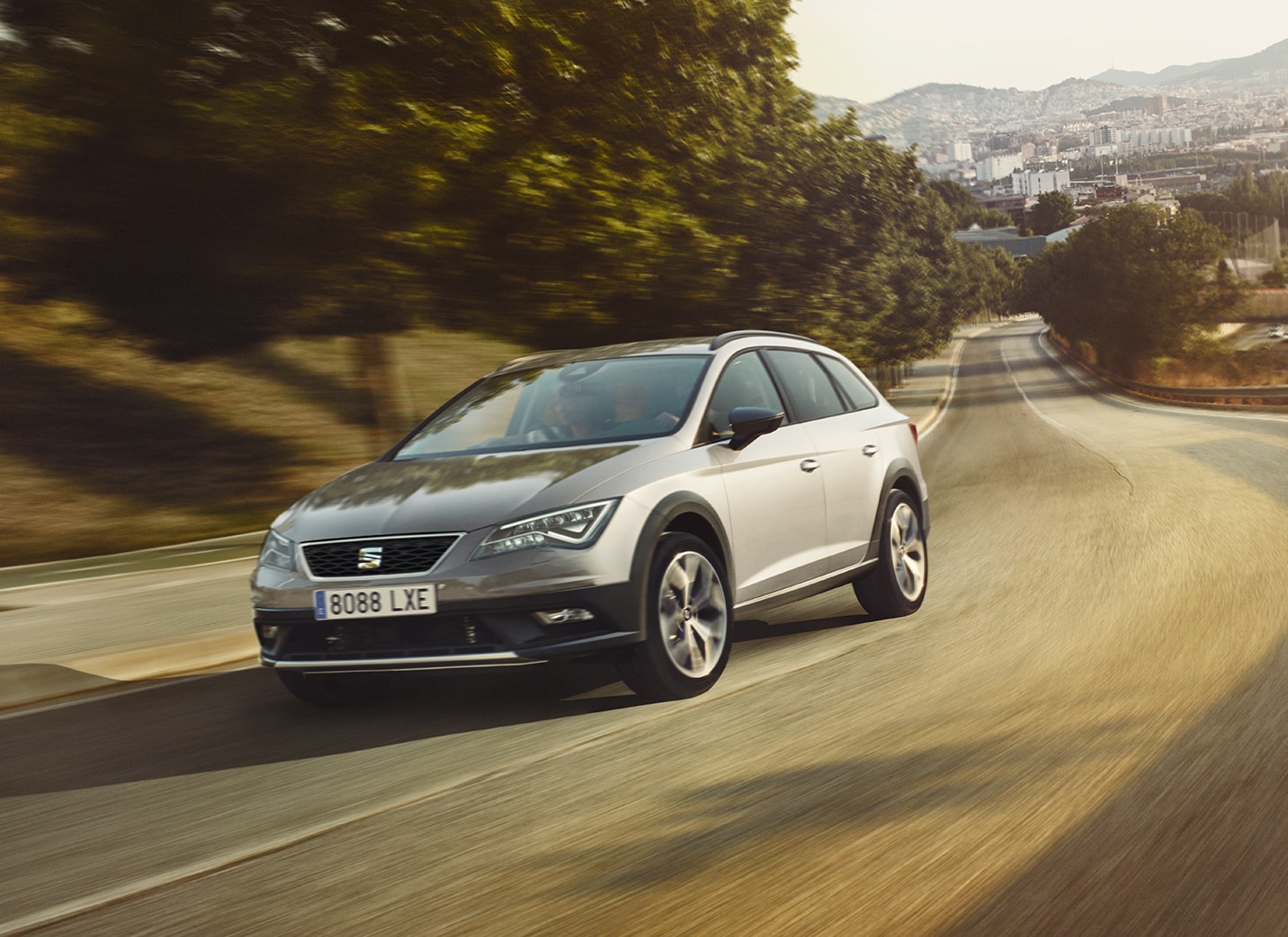 SEAT León en un camino vacío rodeado de campos y árboles.